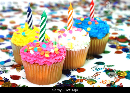 Célébration cupcakes avec bougies et paillettes. Confettis en arrière-plan. Banque D'Images