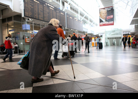 Une vieille femme marche dans le terminal de l'aéroport Franz Josef Strauss, Munich, Allemagne Banque D'Images