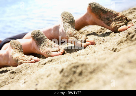 Image de la plante des deux personnes se trouvant sur la plage de sable Banque D'Images