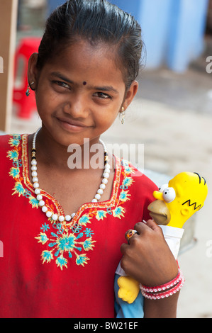 Jeune Indien street girl holding a Homer Simpson poupée. L'Andhra Pradesh, Inde Banque D'Images