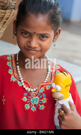 Jeune Indien street girl holding a Homer Simpson poupée. L'Andhra Pradesh, Inde Banque D'Images