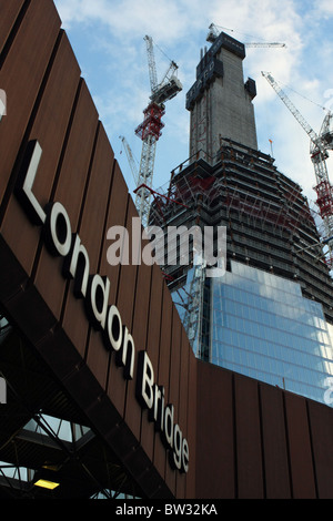 Le tesson de verre de bâtiment en construction, à Londres, avec le 'London Bridge' gare signer au premier plan Banque D'Images