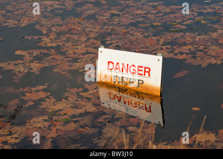 L'eau profonde panneau d'avertissement dans l'étang où le niveau d'eau est de masquer les danger Banque D'Images