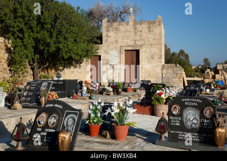 Chapelle de pierre retenu et en fléaux et arrangements floraux mis sur les tombes dans un cimetière dans les îles maltaises. Banque D'Images