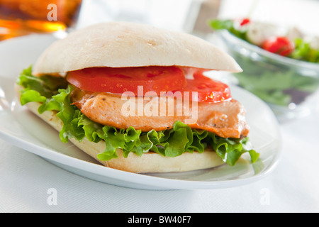 Sandwich au poulet sur plaque blanche, selective focus sur salade et verre sur table top Banque D'Images