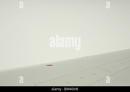 L'aile d'un avion vole à travers les nuages et le brouillard. Banque D'Images