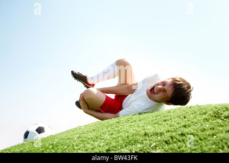 Image de joueur de foot en position couchée et crier de douleur Banque D'Images