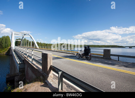 Une moto pour traverser un détroit du lac à l'aide d'un pont-route , Finlande Banque D'Images