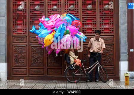 Un ballon salesman standing par portes en bois traditionnel chinois à Kunming, en Chine. Banque D'Images