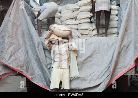 Les hommes indiens sacs de ciment de déchargement d'un camion de chantier de construction. L'Andhra Pradesh, Inde Banque D'Images