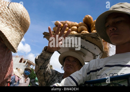 Un vendeur de pain tient cinq doigts tout en portant du pain sur sa tête près de Bavet, au Cambodge. Banque D'Images