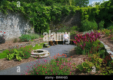 Deux visiteurs se détendre sur un banc dans le jardin en contrebas de la maison du jardin de Buckland Monachorum Devon England UK Banque D'Images