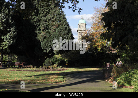 Détente au calme à Bridgnorth Gardens, un couple de personnes âgées profiter de l'ensoleillement de la fin novembre,St Mary's Church tower est visible. Banque D'Images