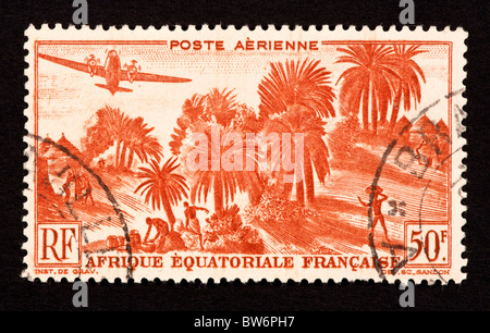 Timbre-poste de l'Afrique Équatoriale Française représentant des palmiers et d'un village. Banque D'Images