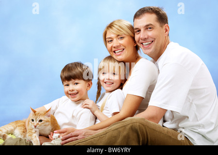 Portrait de famille heureuse looking at camera sur fond bleu Banque D'Images