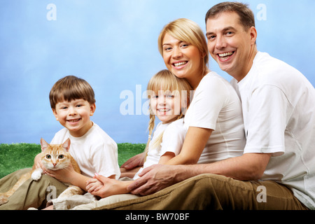 Portrait de famille heureuse et leur animal cute looking at camera sur fond bleu Banque D'Images