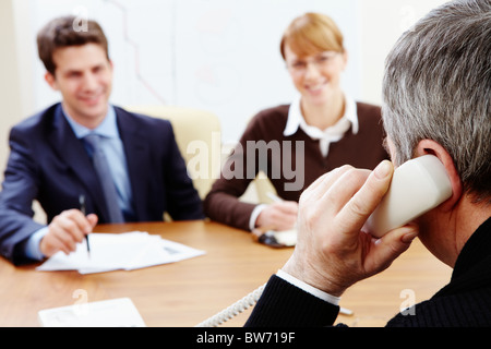 Vue arrière de l'aged businessman à parler au téléphone avec ses employés près de par Banque D'Images