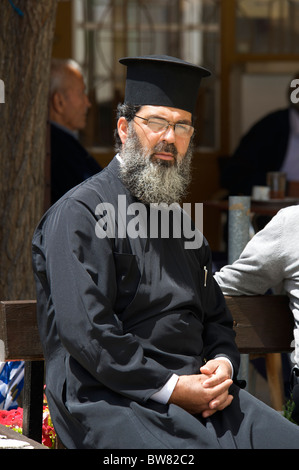 Un moine assis dans un café de la rue, les montagnes de Troodos, République de Chypre Banque D'Images