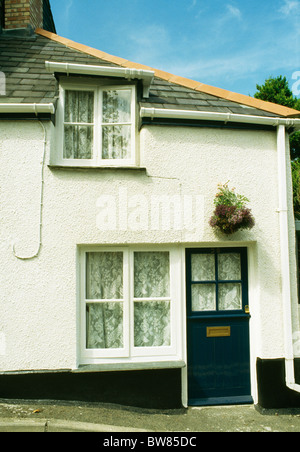 Demi-Noir Porte avant vitrée sur small white cottage avec fenêtres à battant Banque D'Images