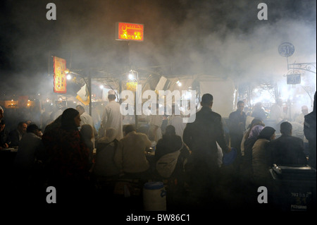 Vapeur et la fumée s'élève de la restauration rapide des stalles et restaurants qui sont mis en place dans la célèbre place Jemaa El Fna à Marrakech Banque D'Images