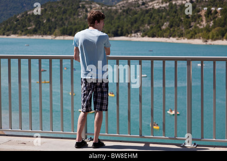 Un adolescent ressemble à partir d'un pont à des vacanciers appréciant pédalo sur le Lac de Sainte Croix dans les Gorges du Verdon, France Banque D'Images