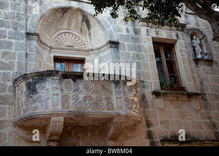 Un vieux bâtiment baroque médiéval avec un balcon en pierre sculpté richement et la niche de Saint Joseph tenant l'enfant Jésus à Malte. Banque D'Images