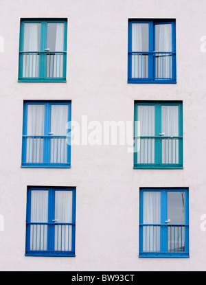 Portes patio bleu et fenêtre, dans un motif sur un mur blanc. Prises en format vertical. Banque D'Images