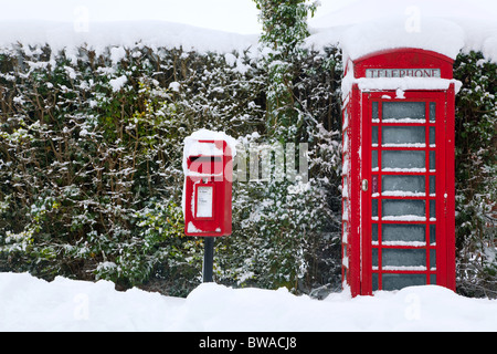 Un téléphone public anglais rouge traditionnel et post box après une forte chute de neige. Banque D'Images