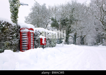 Un téléphone public anglais rouge traditionnel et post box après une forte chute de neige. Banque D'Images