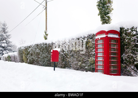 Un téléphone public anglais rouge traditionnel et post box après une forte chute de neige. Banque D'Images