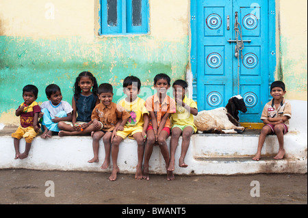 Les garçons et les filles du village indien est assis à l'extérieur d'une chambre avec une chèvre dans l'ancien village de Puttaparthi, Andhra Pradesh, Inde Banque D'Images