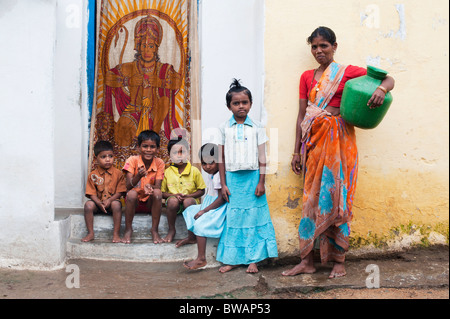 Les garçons et les filles du village indien est assis à l'extérieur d'une maison avec une mère à aller chercher de l'eau à Puttaparthi, Andhra Pradesh, Inde Banque D'Images