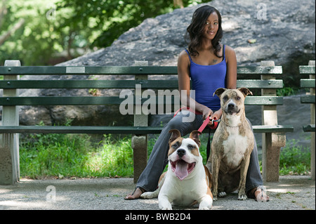 Femme assise sur le banc de parc avec ses deux chiens Banque D'Images