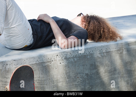 Young woman lying on wall