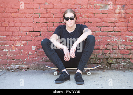 Skater sitting on board Banque D'Images