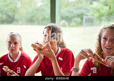 Les joueurs de soccer Girl eating pizza Banque D'Images