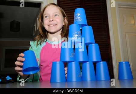 Jeune fille jouant à l'aide de piles de vitesse tasses empilables bleu Banque D'Images