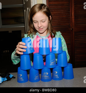 Jeune fille jouant à l'aide de piles de vitesse tasses empilables bleu Banque D'Images