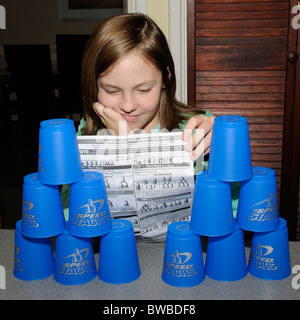 Jeune fille lisant notice comme elle apprend à jouer Speed Stacks Banque D'Images