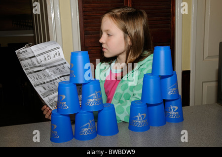 Jeune fille lisant notice comme elle apprend à jouer Speed Stacks Banque D'Images