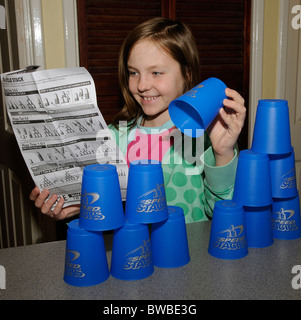 Jeune fille lisant notice comme elle apprend à jouer Speed Stacks Banque D'Images