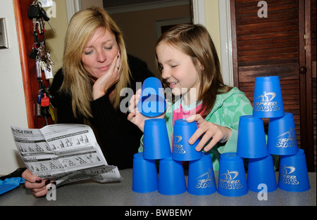 Jeune fille jouant avec des piles de vitesse de lecture de la notice d'instruction de la mère Banque D'Images