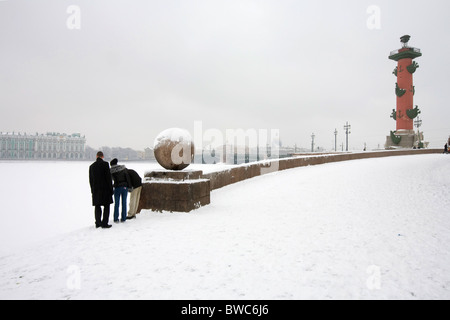 Trois jeunes gens à la recherche dans la neige de la Néva en face du "Palais d'hiver', St Petersburg, Russia Banque D'Images