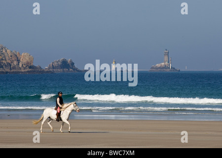 Horse Rider sur la plage à la baie de Trépassés, avec le Cap Sizun, la Pointe du Raz et phare de la veille. Octobre 2007. Banque D'Images