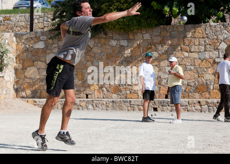 Un homme joue aux boules (pétanque), alors que d'autres joueurs. Provence, France. Banque D'Images