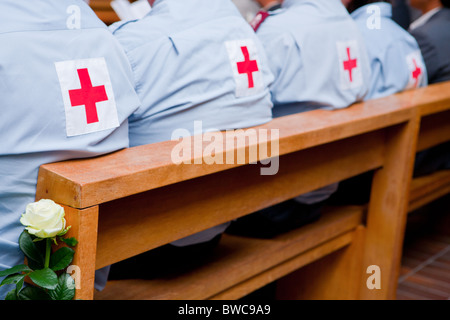 Volontaires de la Croix-Rouge assis sur un banc d'église avec une rose blanche Banque D'Images