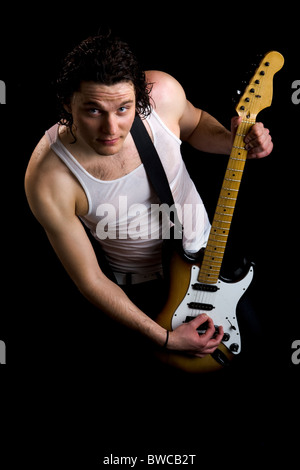 Portrait de guitar player in vest holding instrument sur fond noir Banque D'Images