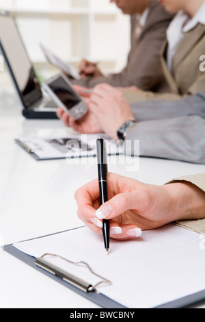 Image main de femme de stylo à bille sur papier avec l'écriture sur fond de travailleurs Banque D'Images