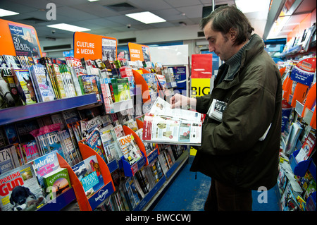 Un homme l'exploration d'une sélection de magazines hebdomadaires et mensuels dans une succursale de W.H.Smith marchands UK Banque D'Images