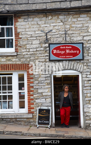 Woman standing in doorway de Corfe Castle boulangerie du village, château de Corfe, Dorset UK en Septembre Banque D'Images